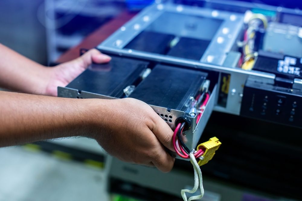 A person is taking a battery out of a computer.