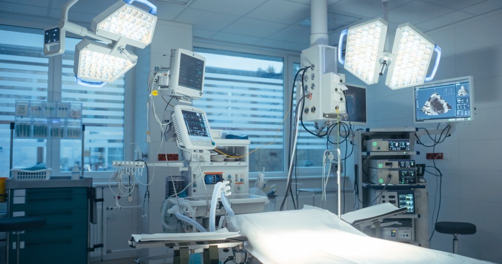 An empty operating room with a bed and lots of medical equipment.