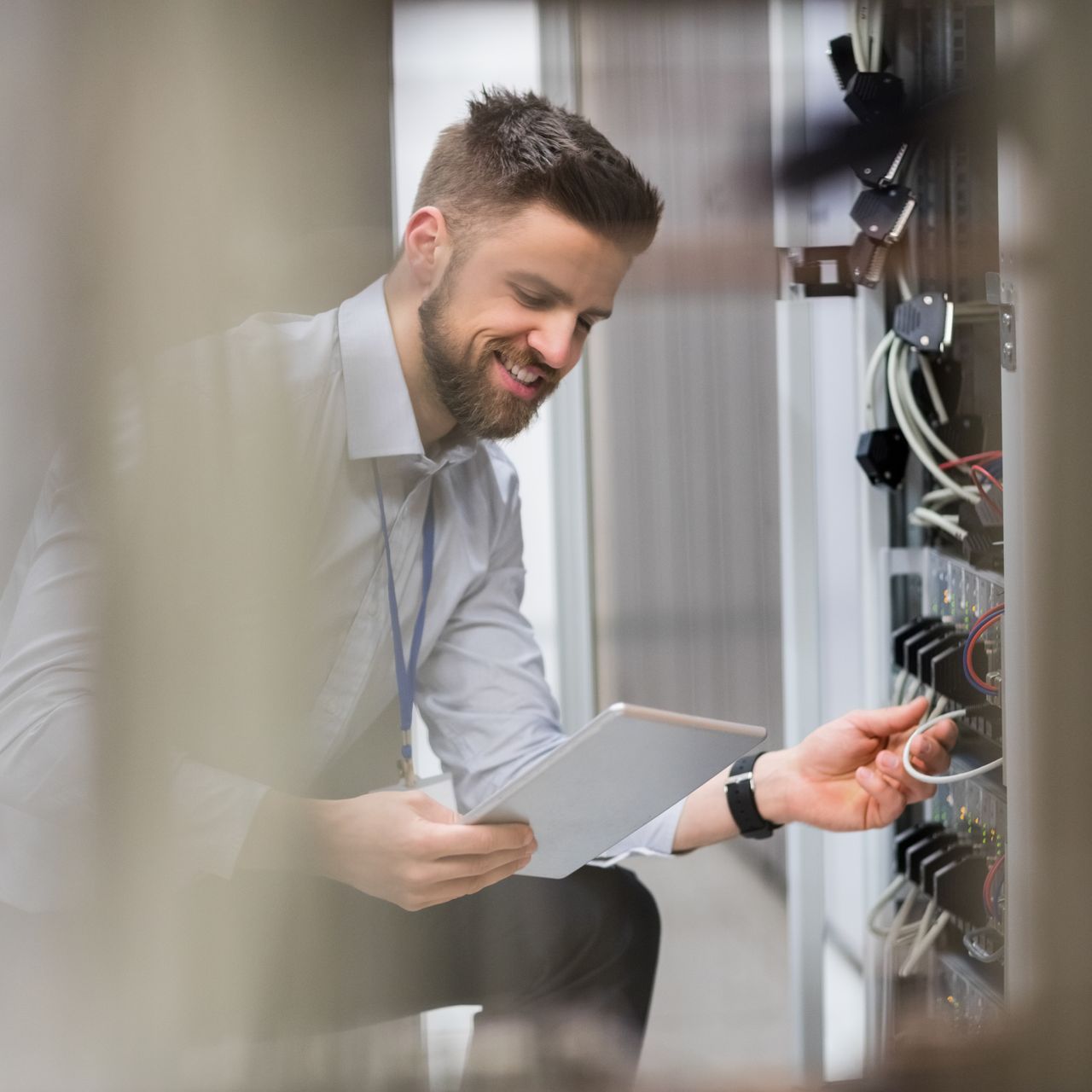 A man is looking at a tablet while working on a server.