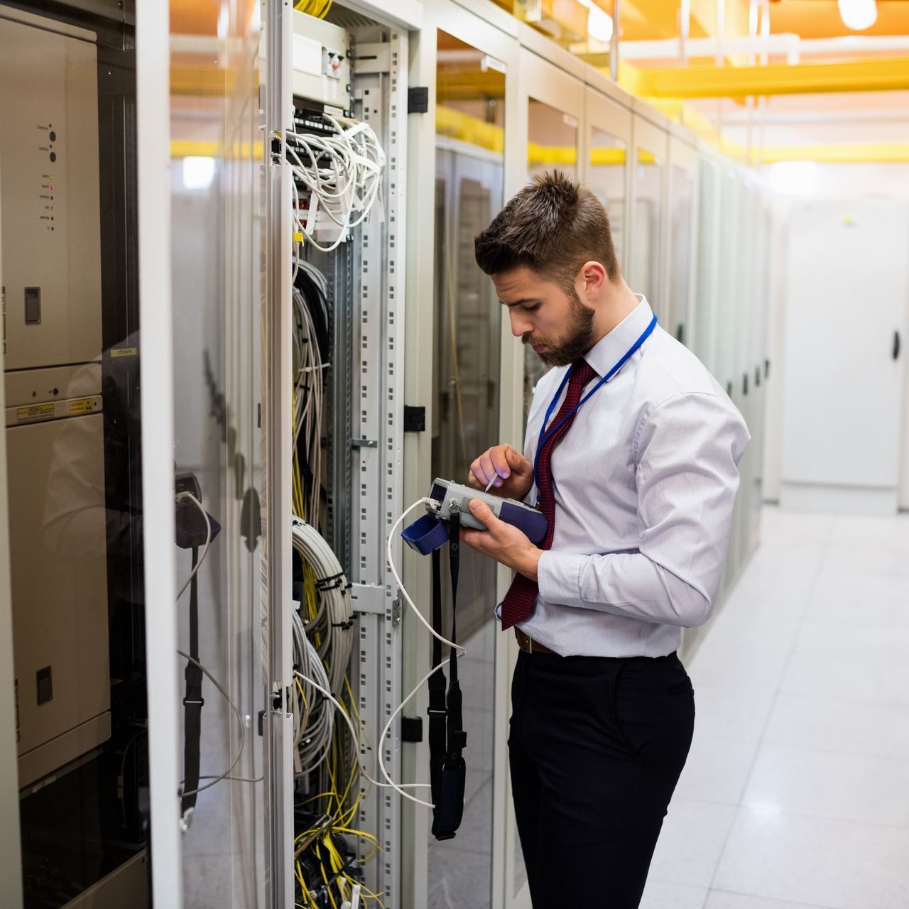 A man in a white shirt and tie is working on a server