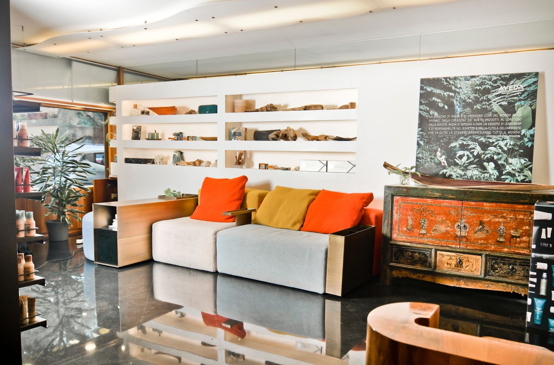 Soggiorno con divano e scaffali integrati, pavimento scuro e un mobiletto decorativo.