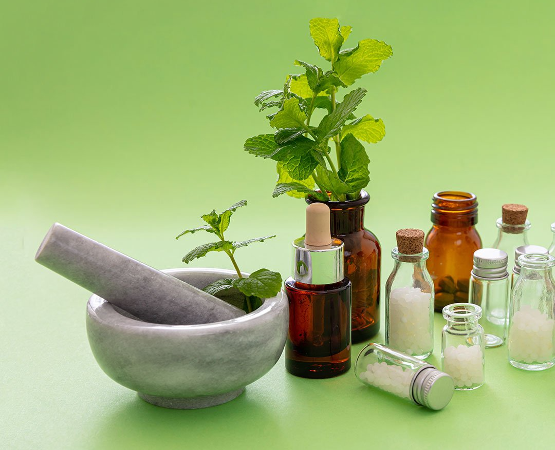 Ein Mörser und Stößel, umgeben von Flaschen und Pflanzen auf einem grünen Tisch.