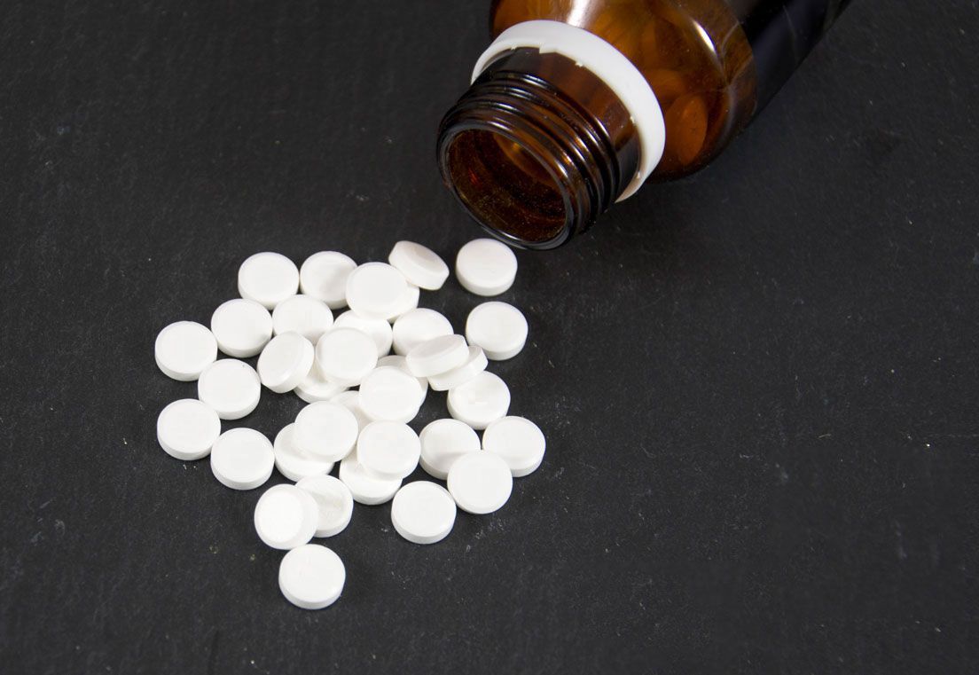 Eine braune Flasche, aus der weiße Pillen fließen