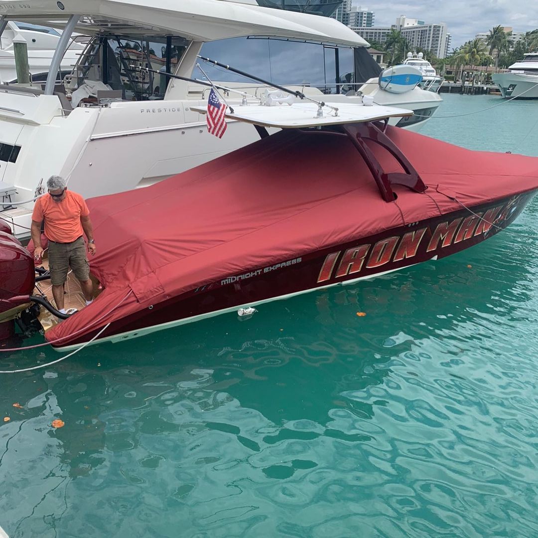 A man is standing next to a red boat in the water.