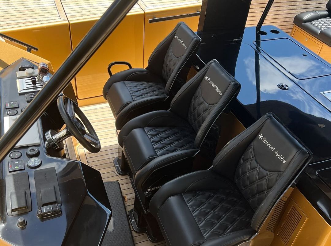 The inside of a boat with black seats and a steering wheel