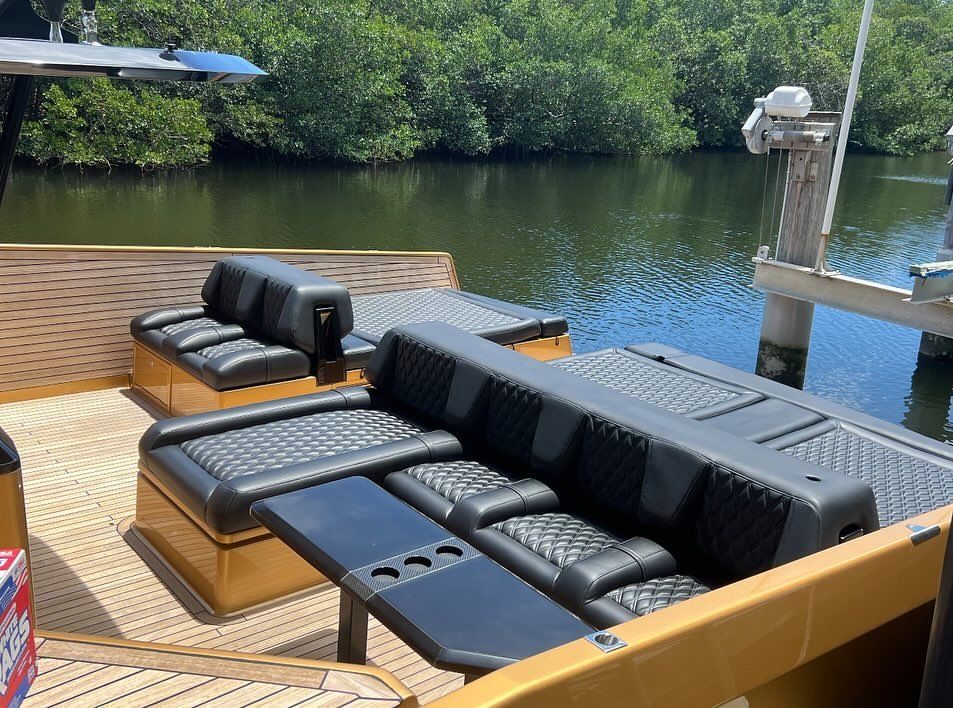 A boat is docked at a dock with a couch and table on the deck.