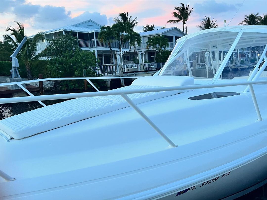 A white boat is docked in a marina with palm trees in the background.