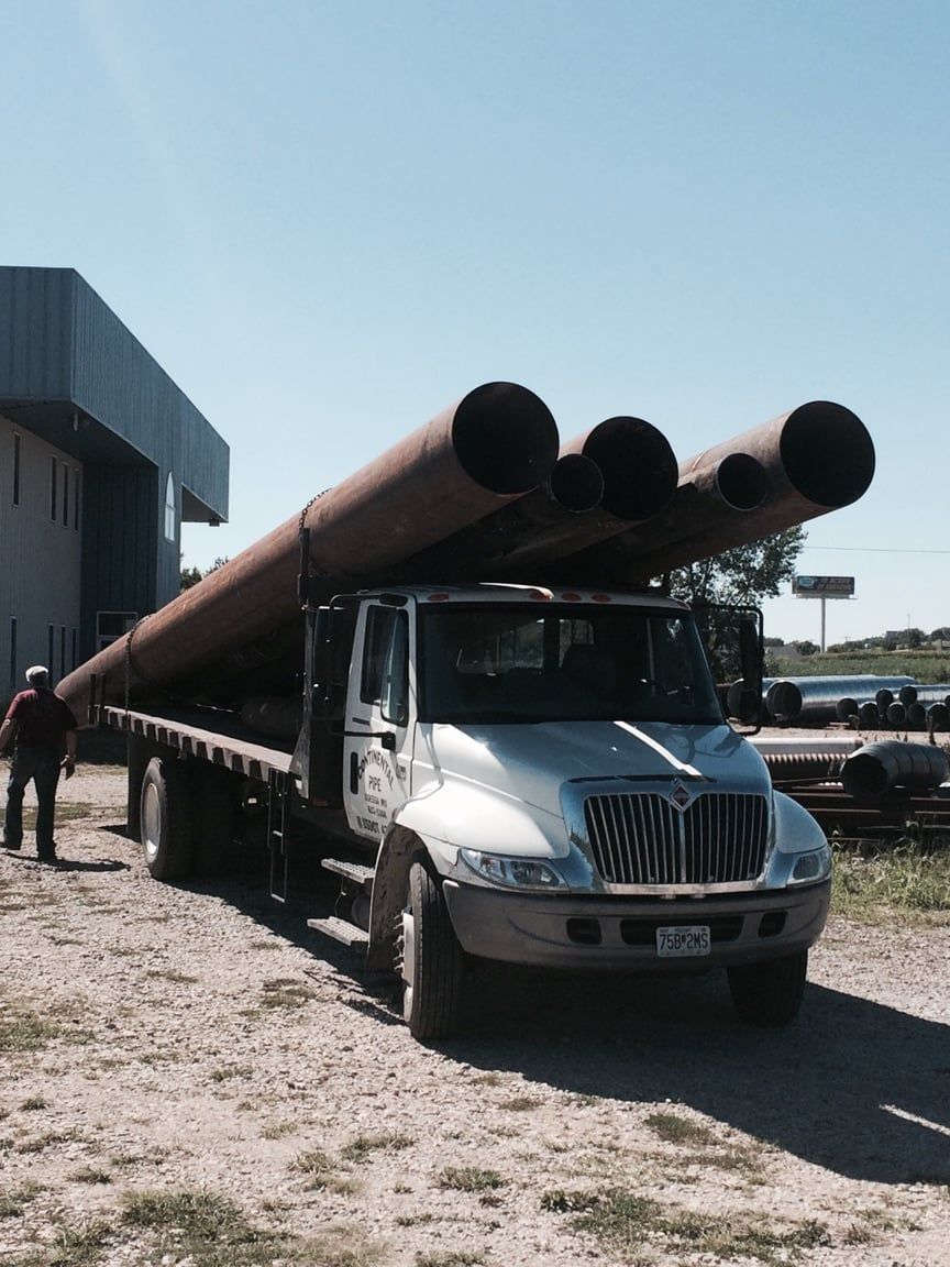 A white truck is carrying a load of pipes — Odessa, MO — Continental Pipe Co.