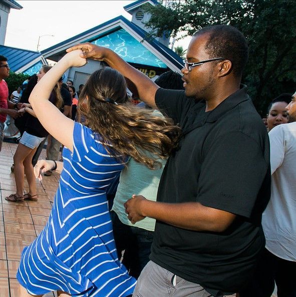 A woman in a blue striped dress is dancing with a man in a black shirt