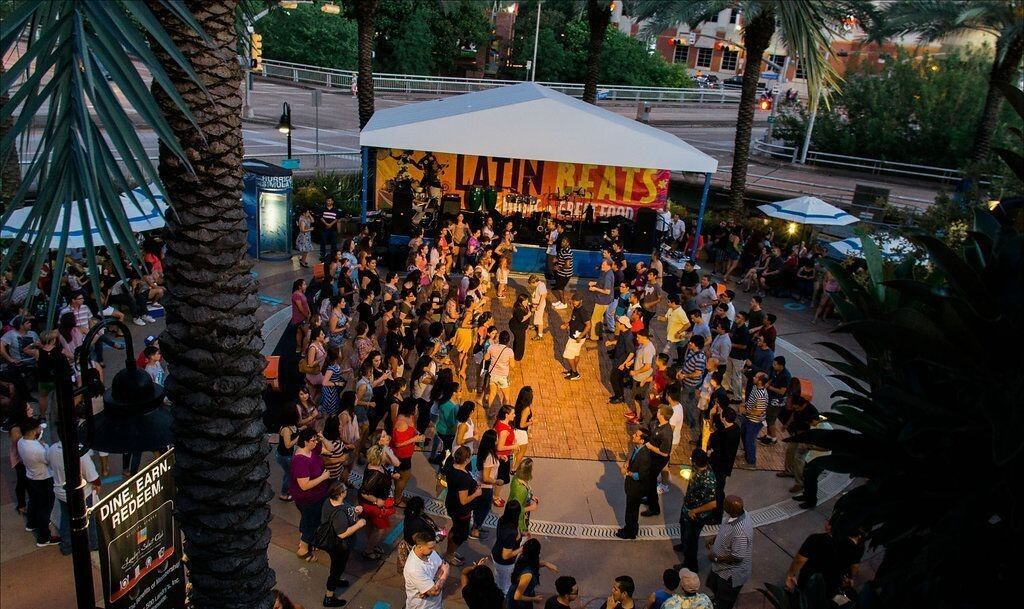 A crowd of people are gathered in front of a stage dancing
