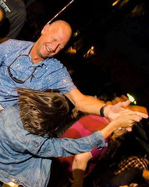 A man in a blue shirt is holding a child in his arms