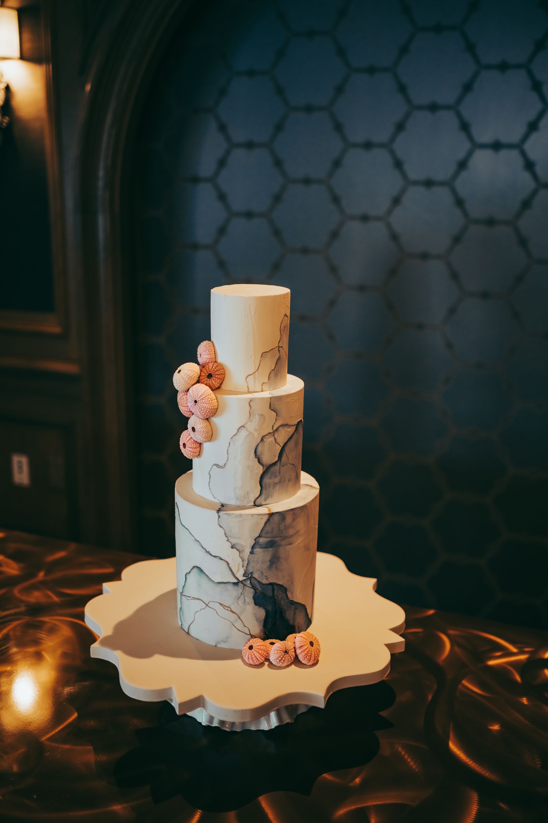 A wedding cake is sitting on a table in front of a blue wall