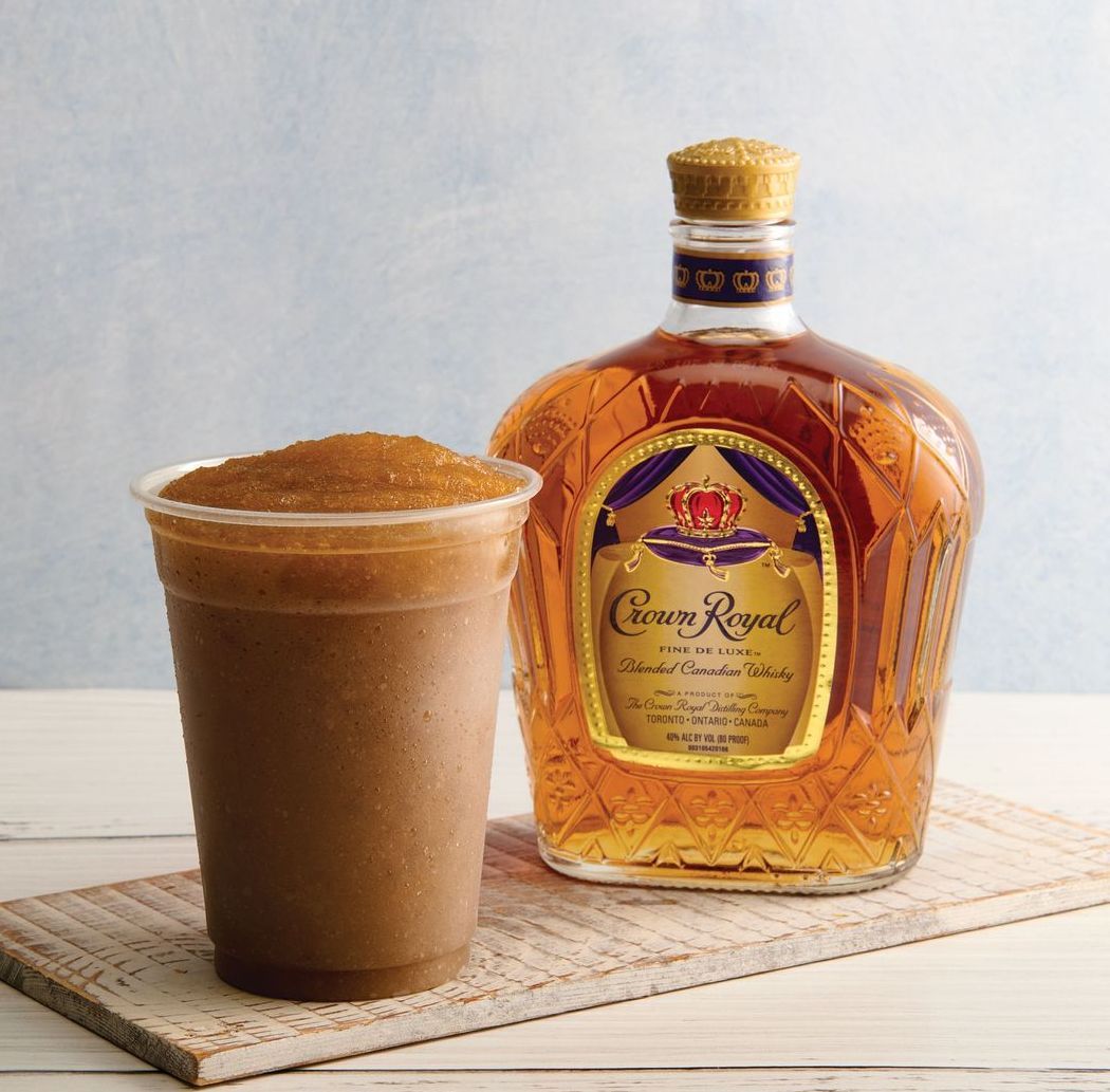 A bottle of crown royal next to a cup