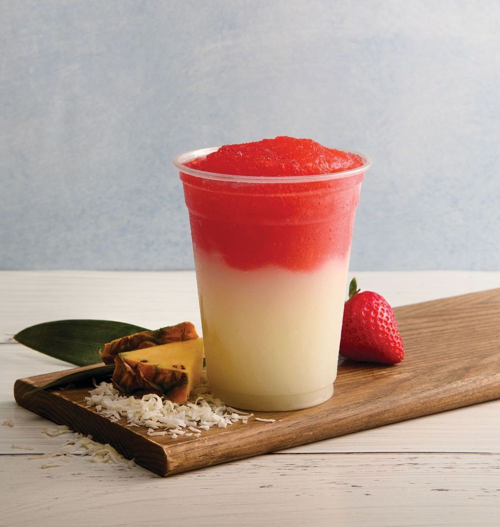 A strawberry and pineapple smoothie in a plastic cup