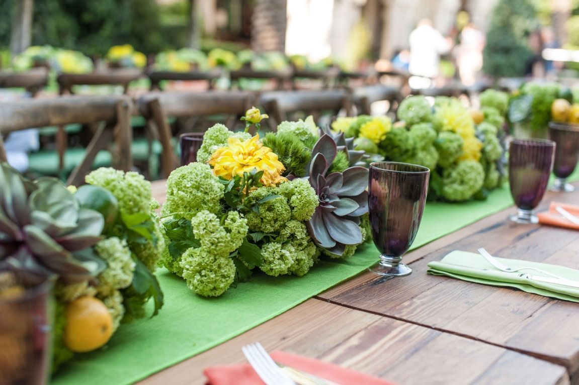 A wooden table with flowers and glasses on it