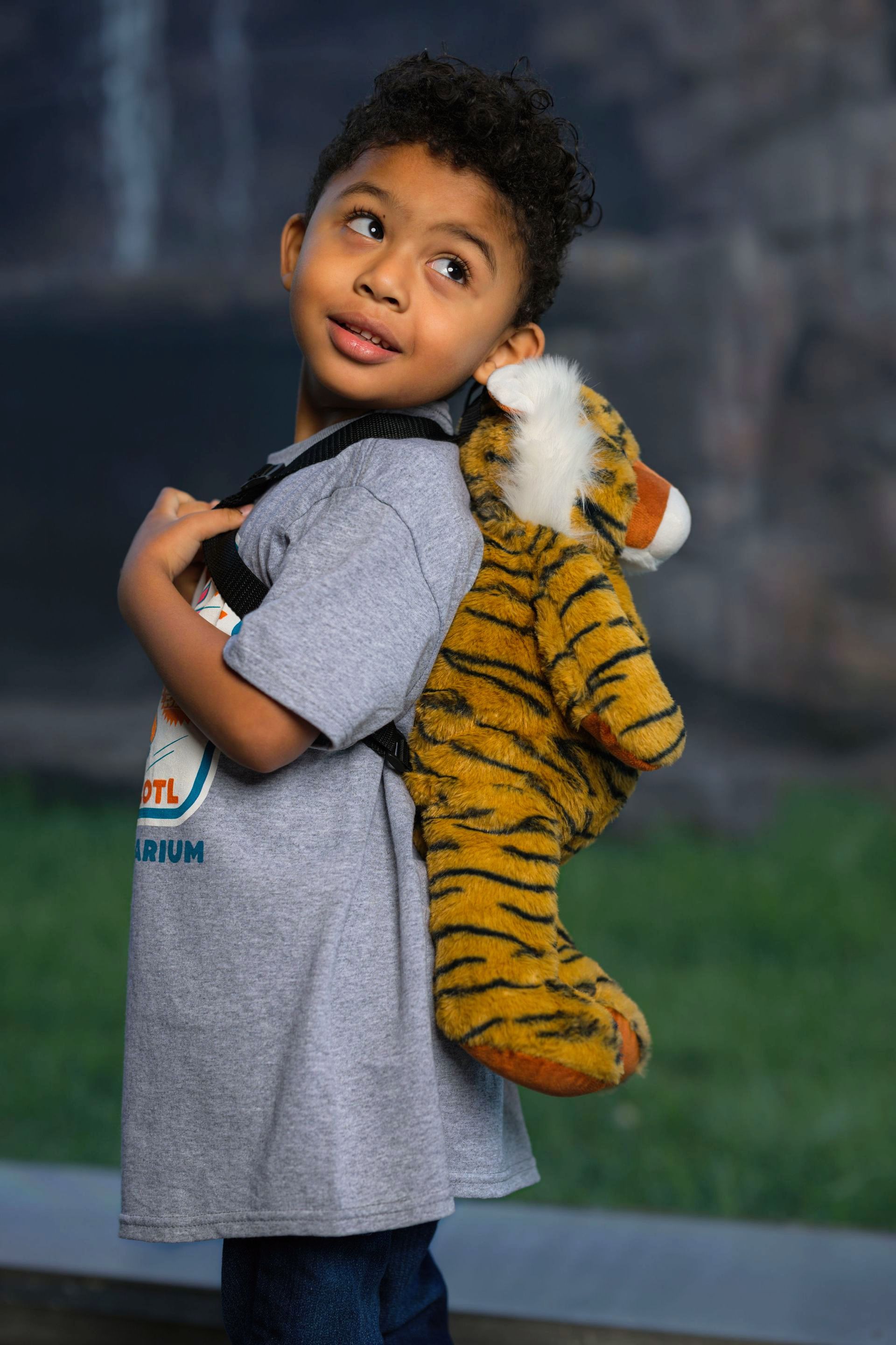 A young boy is carrying a stuffed tiger on his back