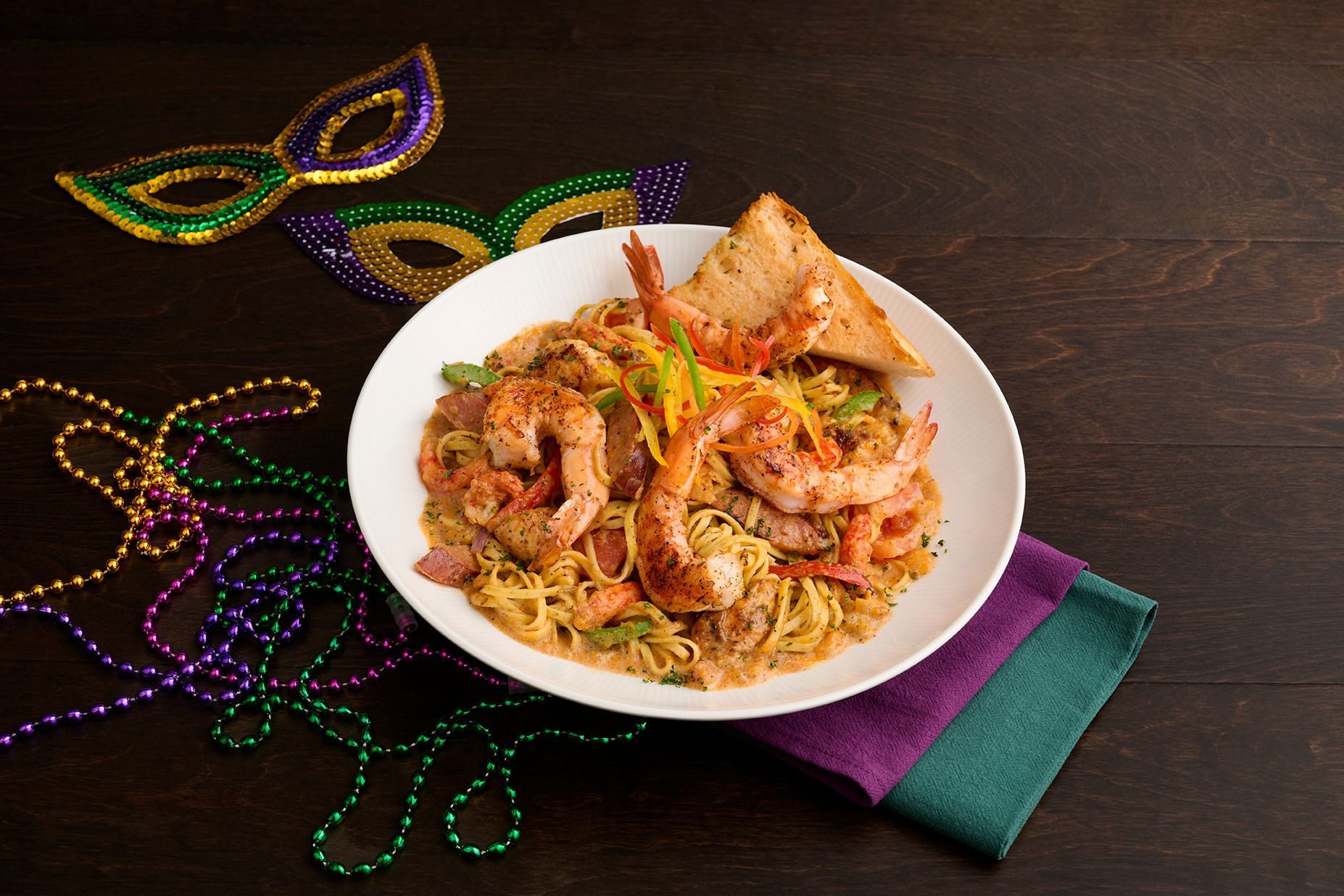 Plate of shrimp pasta with Mardi Gras decorations.