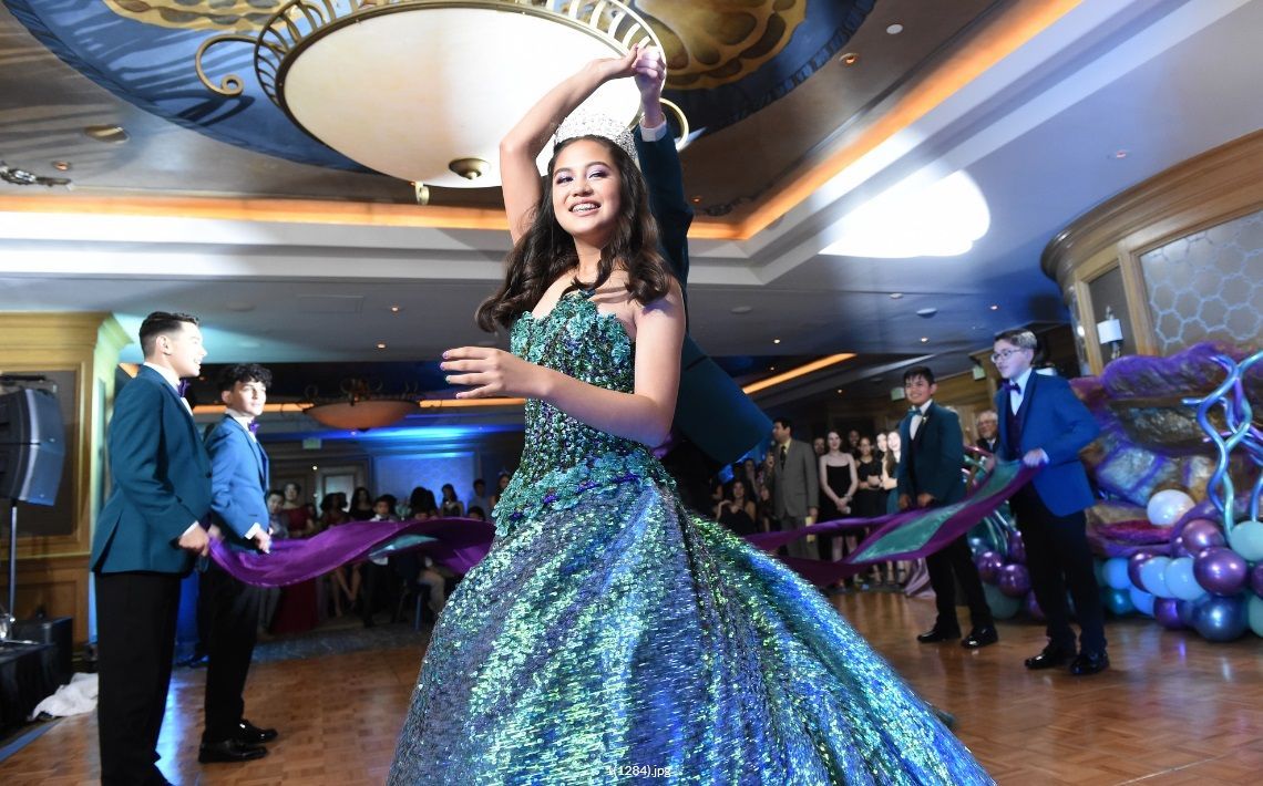 A woman in a green dress is dancing with a man in a blue suit.