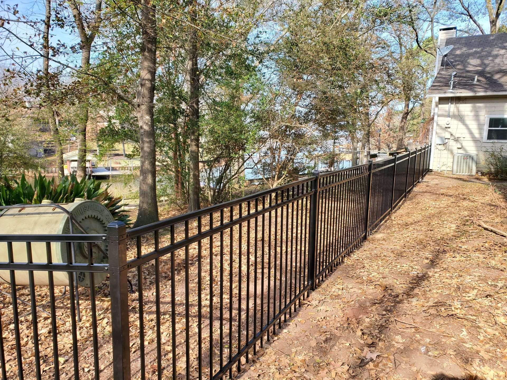 A black metal fence surrounds a yard next to a house.