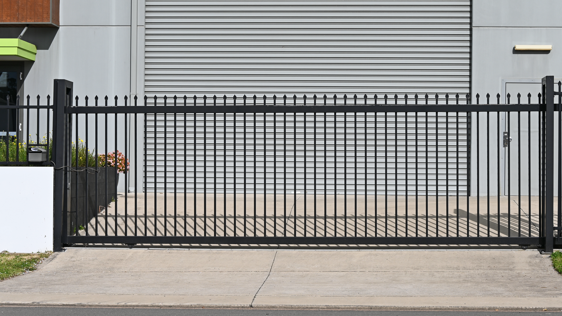 A black sliding gate is open in front of a building