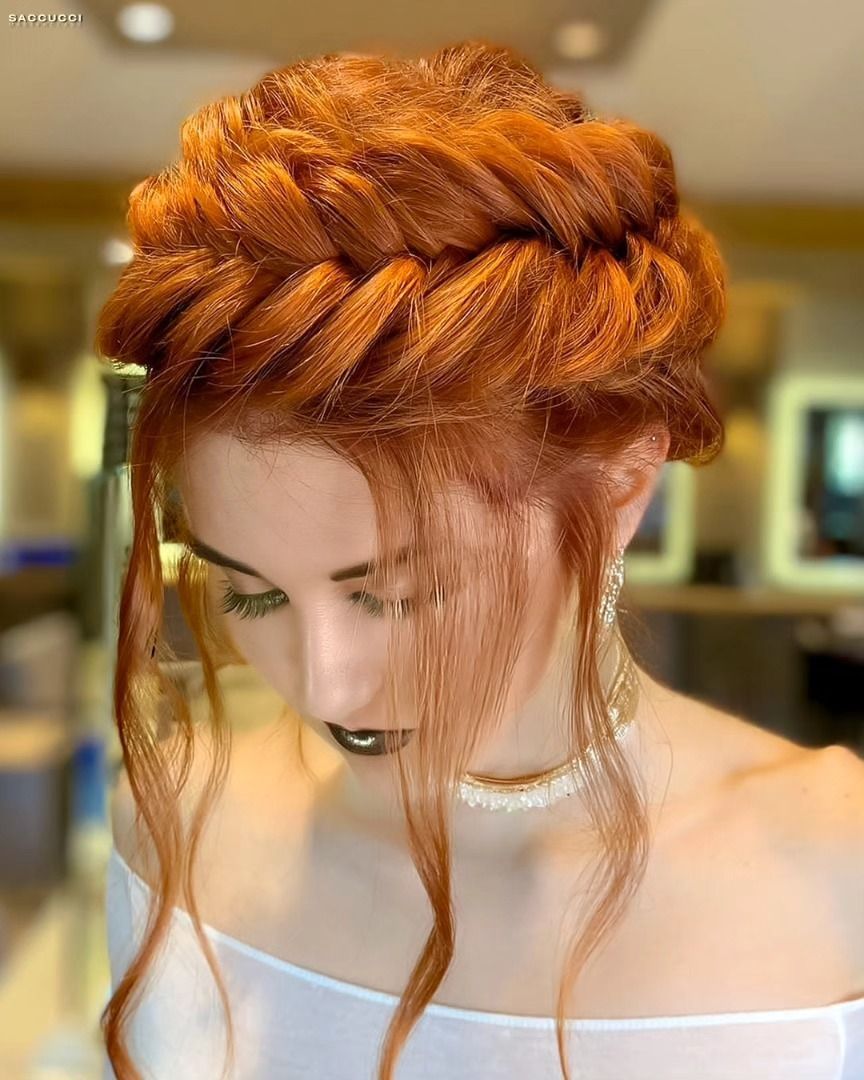 Primo piano di una persona con lunghi capelli rosso vivo, acconciati in una treccia a corona spessa e decorativa.