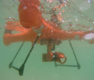 Une personne nage dans une piscine avec un drone dans l'eau.