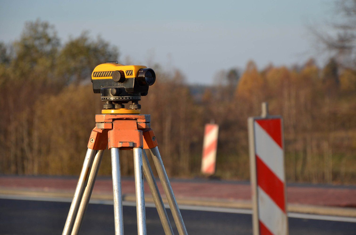 Un niveau sur un trépied est posé sur le bord d'une route.