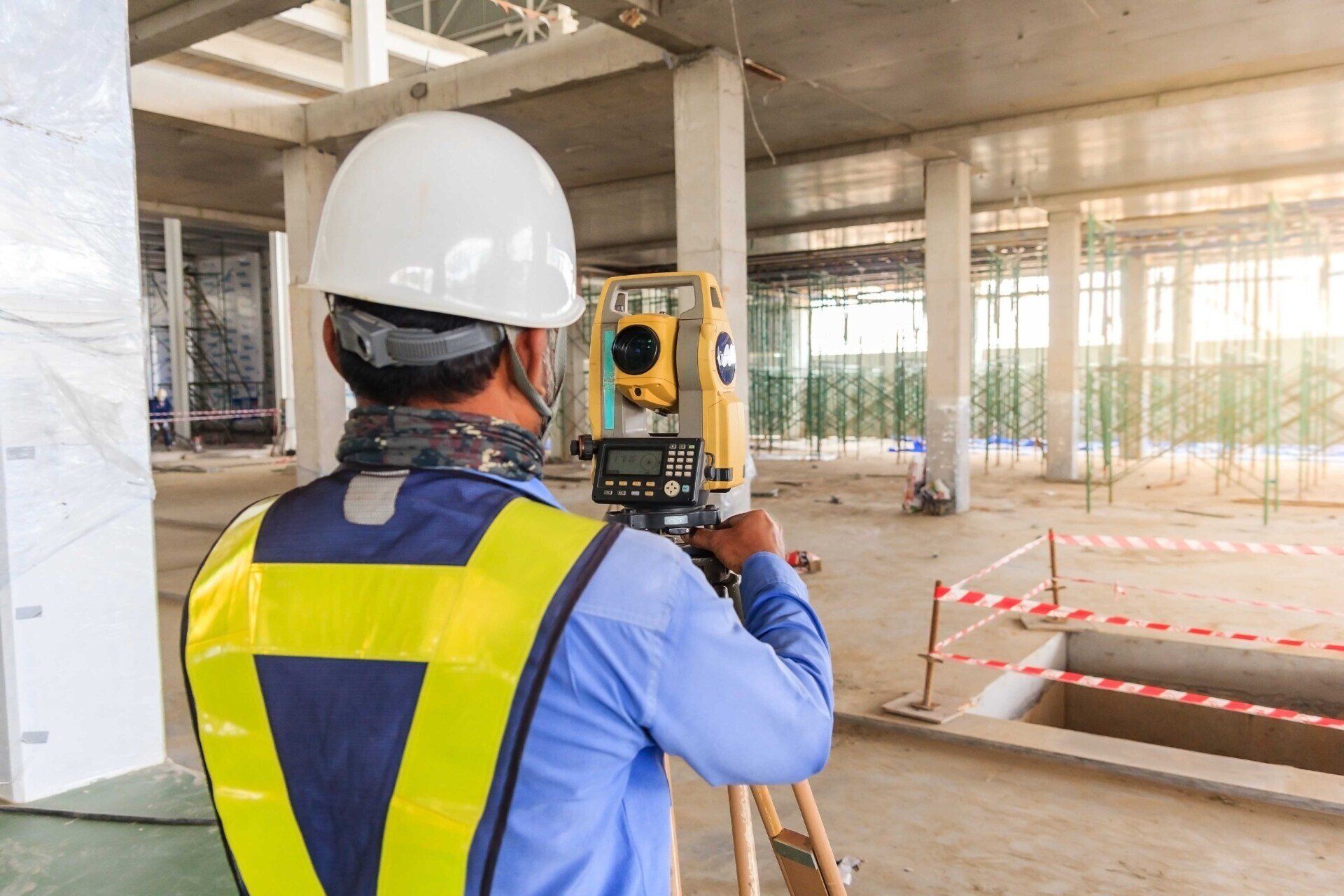 Un ouvrier du bâtiment utilise une station totale dans un bâtiment en construction.