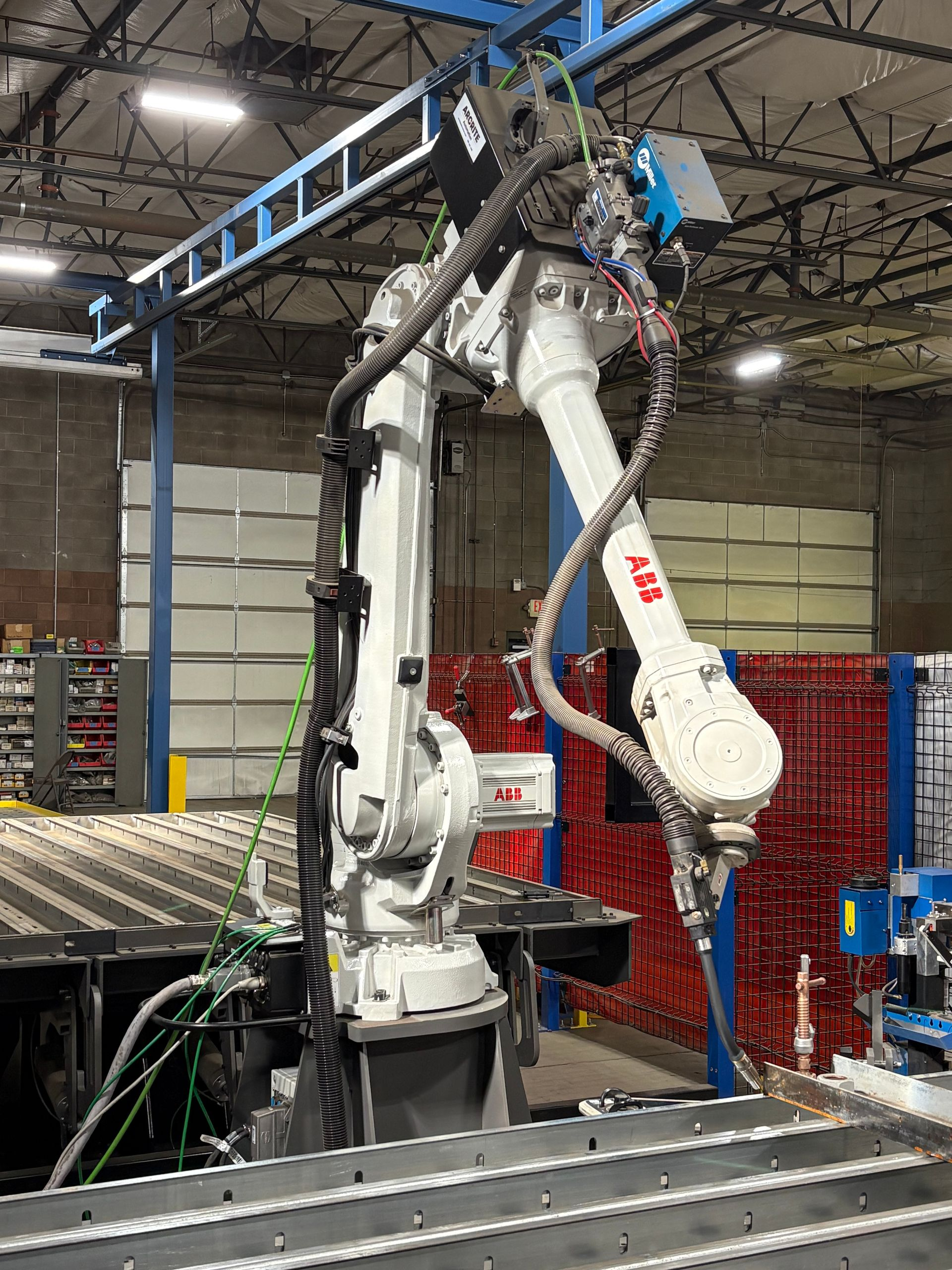 White robotic arm welding metal in a factory setting.