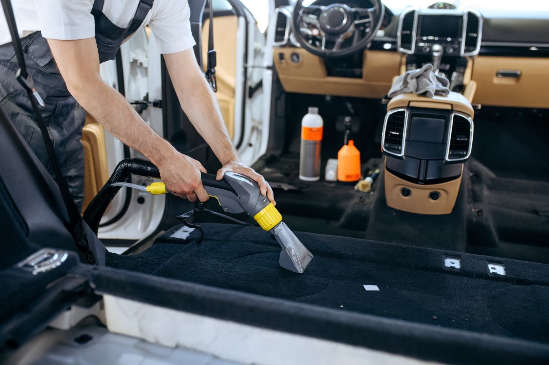 A man is cleaning the interior of a car with a vacuum cleaner.