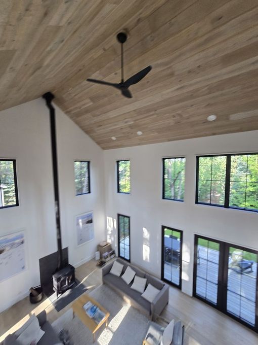 Bright, airy living room with high ceilings, wood paneling, and large windows. 