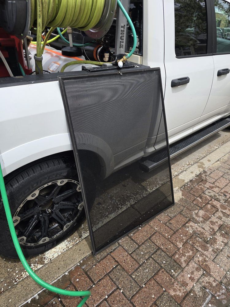 A screen lying on a brick surface next to a white truck with a green hose.