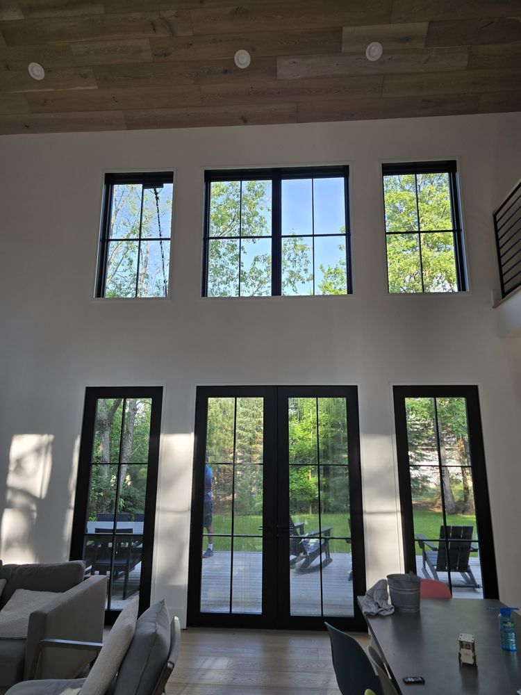 High-ceilinged room with black-framed windows and French doors.