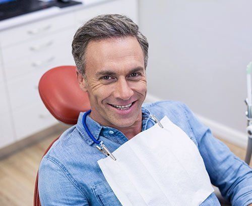 A man is smiling while sitting in a dental chair.