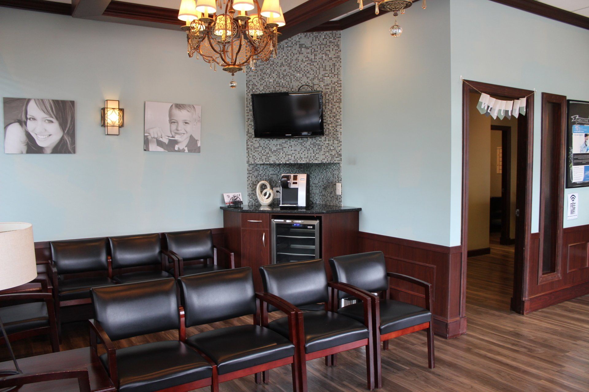 A waiting room with chairs , a television and a chandelier.