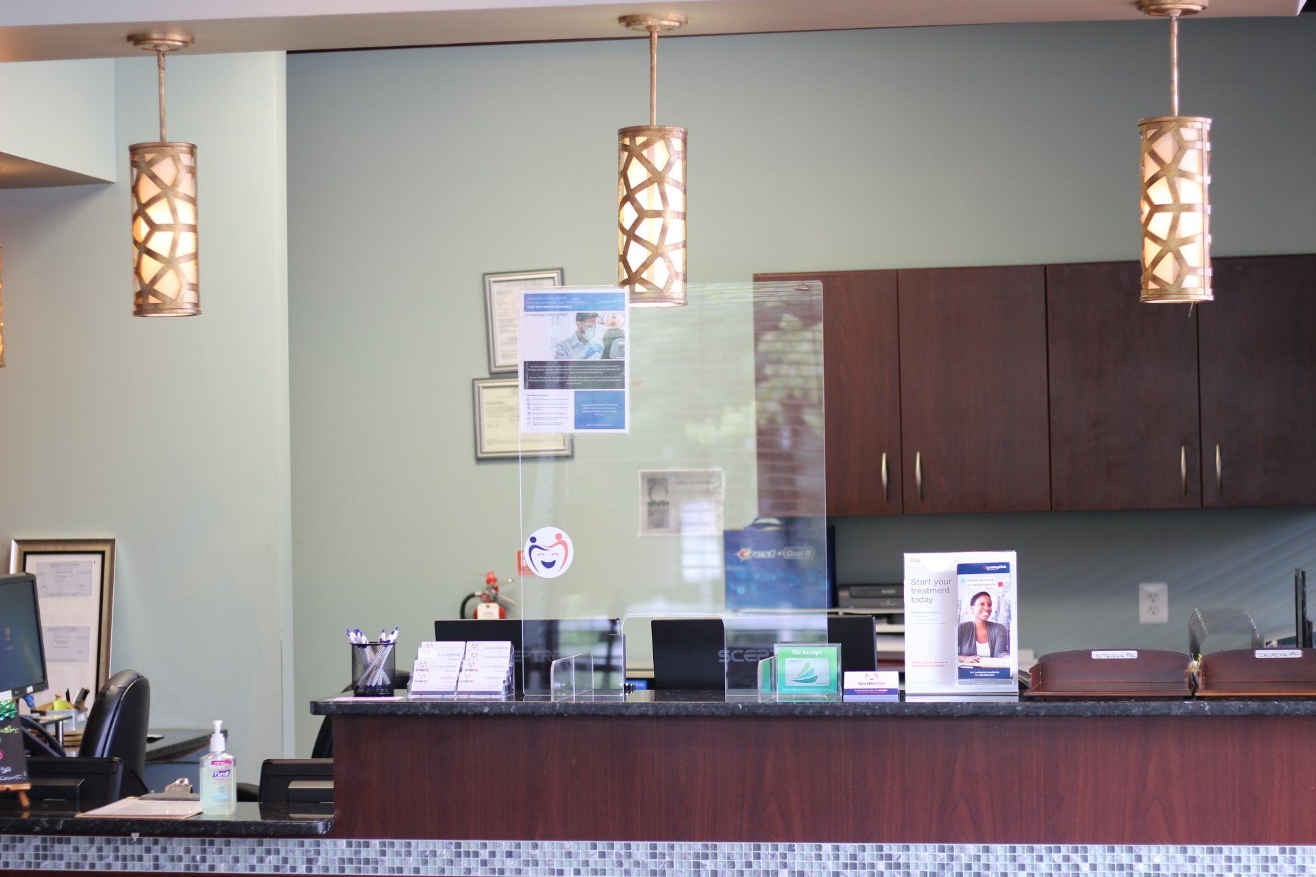 The front desk of a dental office with a glass barrier