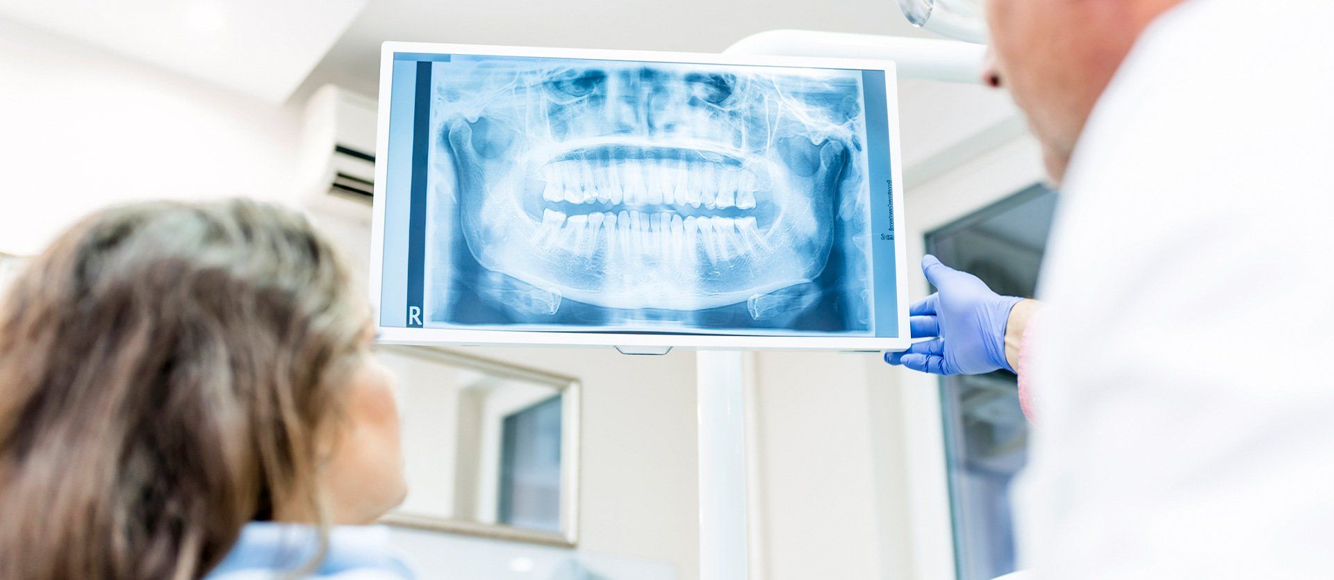 A dentist is looking at an x-ray of a patient 's teeth.