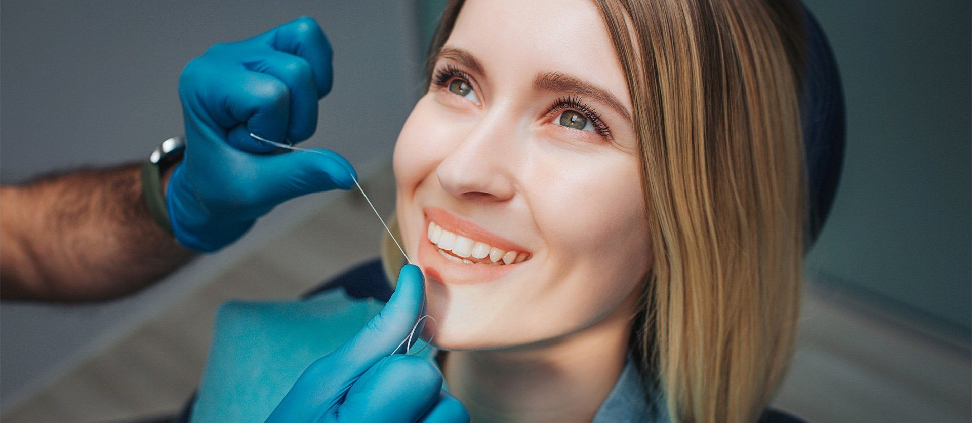 A woman is smiling while having her teeth examined by a dentist.