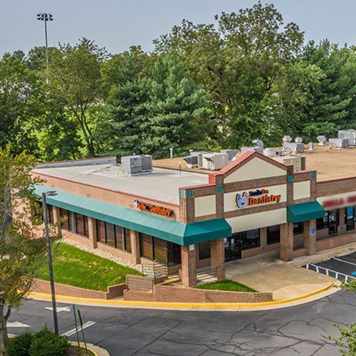 An aerial view of a brick building with a blue awning surrounded by trees.