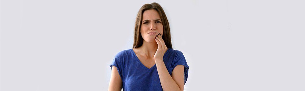 A woman is holding her face in pain because of a toothache.
