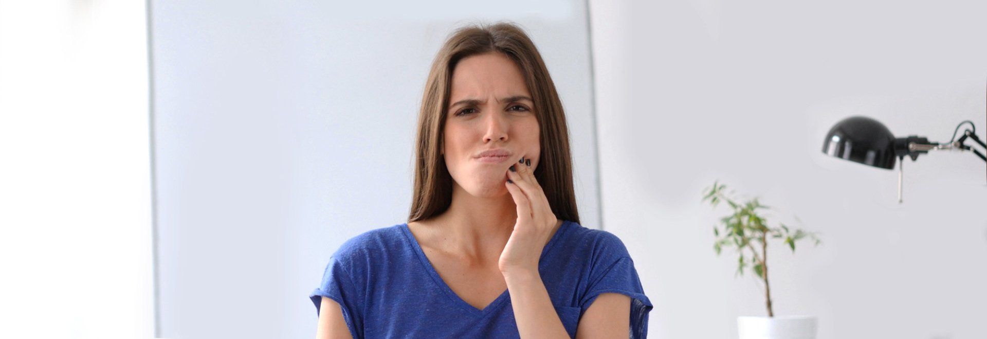 A woman is holding her face in pain because of a toothache.