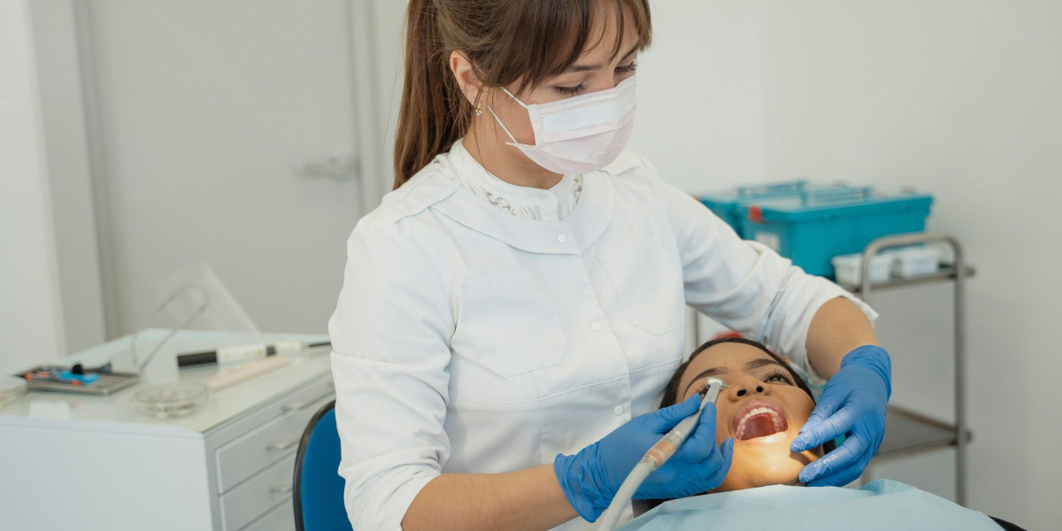 Hand applying whitening gel to clear teeth whitening trays on a white surface.