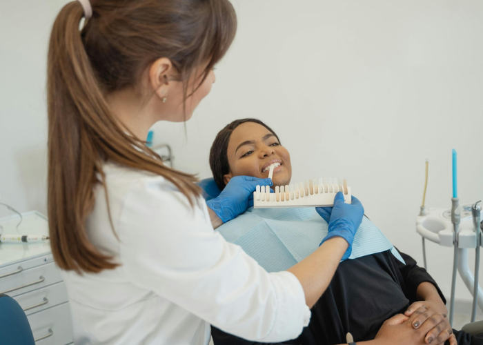 Dentist comparing patient's teeth to a shade guide in a dental office.