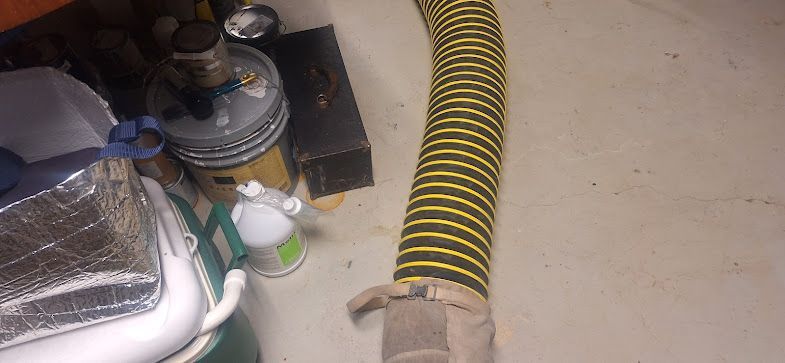 A yellow and black hose is sitting on the floor in a garage.