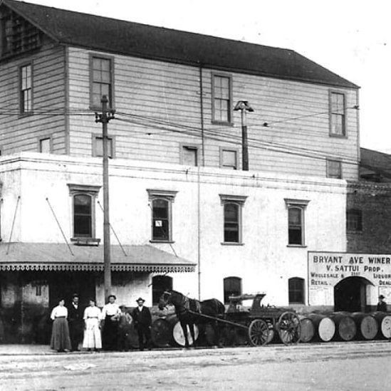 Bryant Ave. Wines building with people, horse-drawn cart, and barrels.
