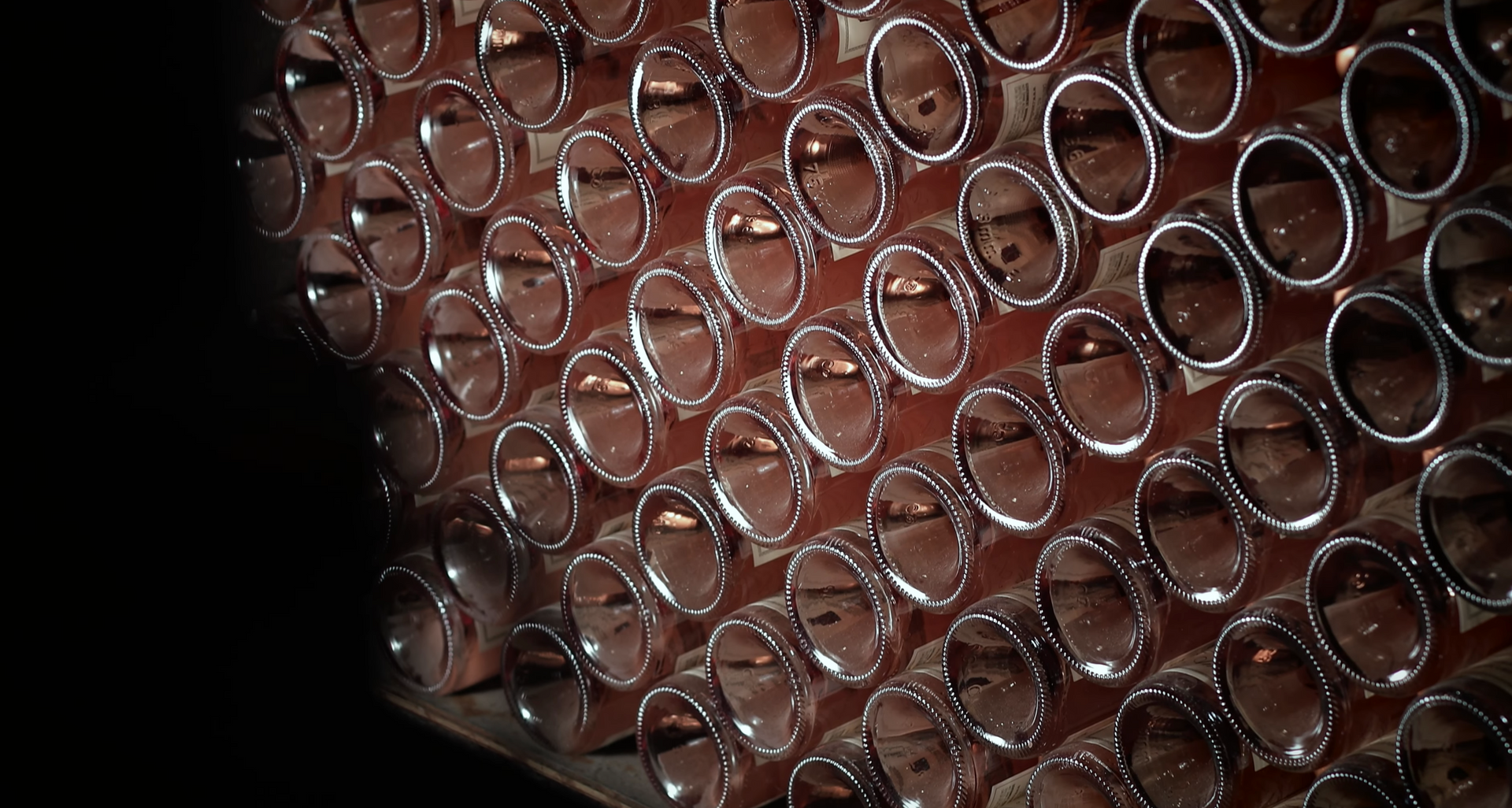 Rows of glass tubes reflecting light, mounted on a wooden frame.