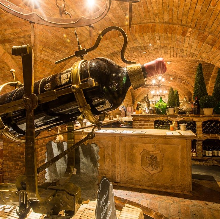 Wine cellar with large bottle display. Stone walls, bar, and arched ceiling.