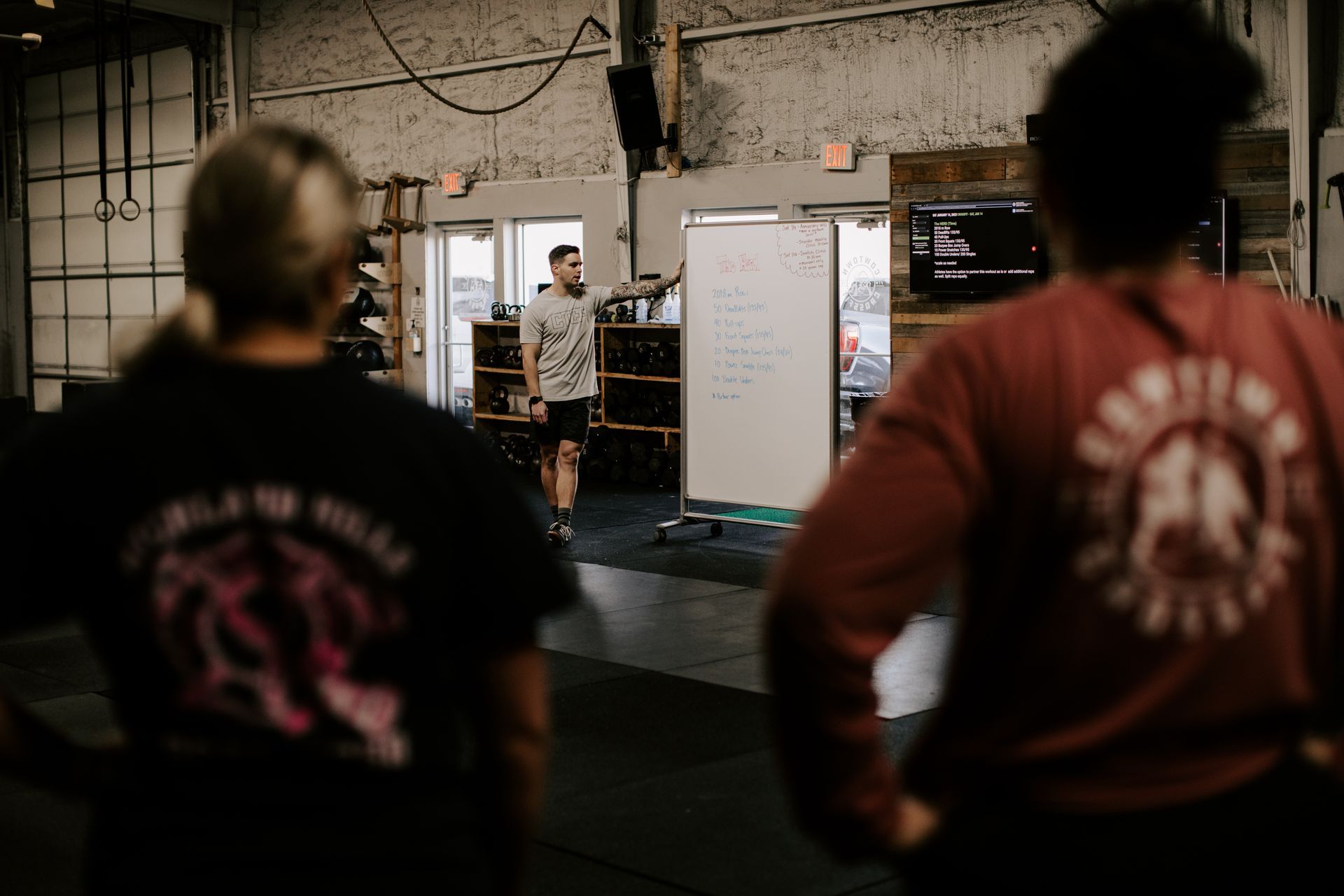 A man and a woman are standing in a gym talking to each other.
