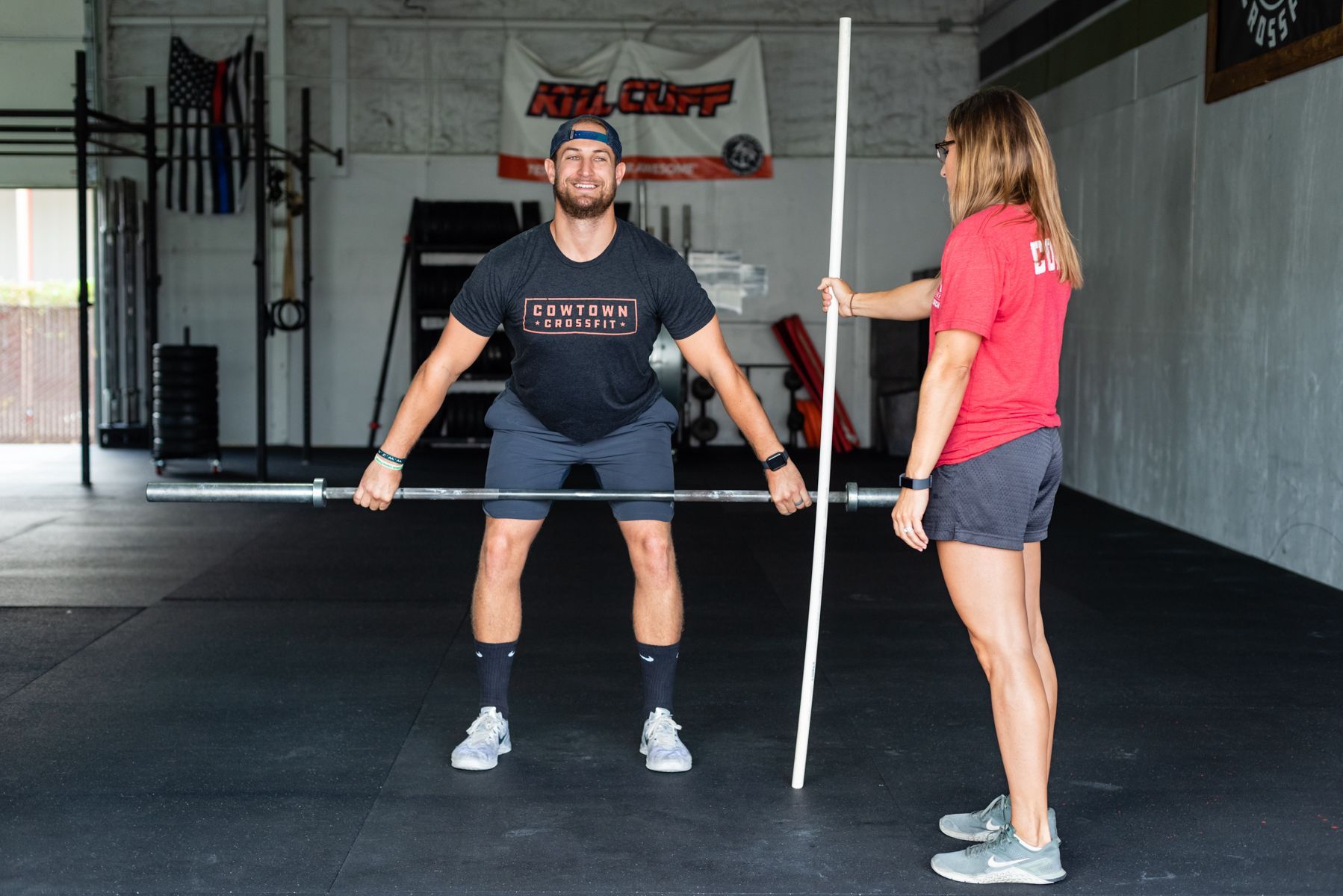 A man and a woman are measuring each other in a gym.