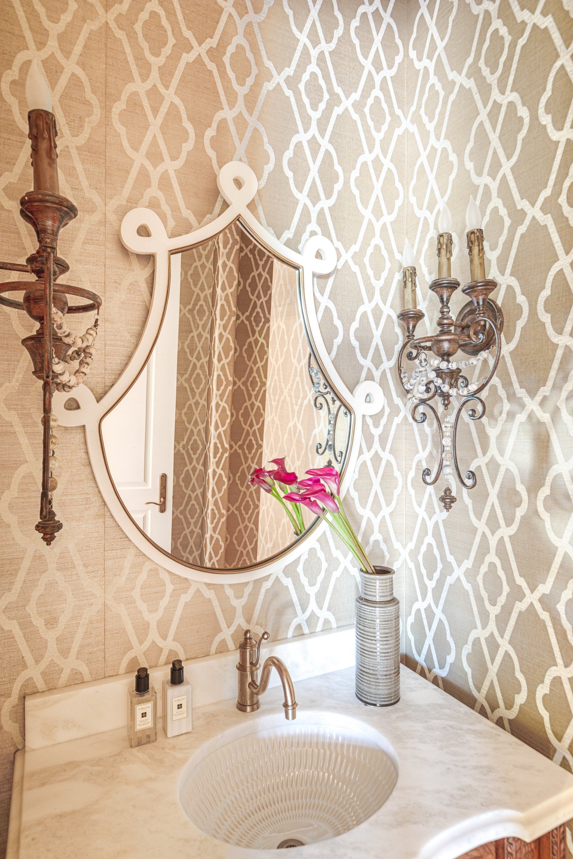 A bathroom with a sink, mirror and candles.